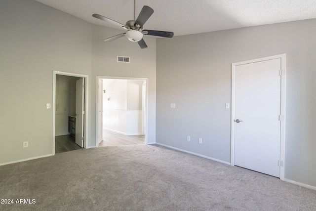 unfurnished bedroom featuring connected bathroom, ceiling fan, high vaulted ceiling, light colored carpet, and a textured ceiling