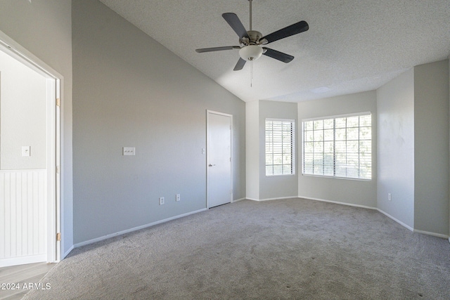 carpeted spare room featuring a textured ceiling, vaulted ceiling, and ceiling fan