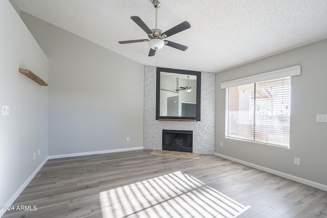 unfurnished living room featuring ceiling fan, a fireplace, wood-type flooring, and a textured ceiling