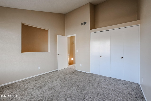 unfurnished bedroom featuring lofted ceiling, a closet, and carpet flooring