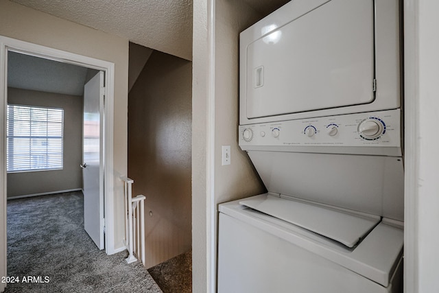 laundry area with dark carpet, a textured ceiling, and stacked washer / dryer