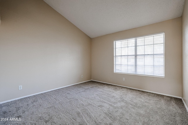 carpeted empty room featuring vaulted ceiling