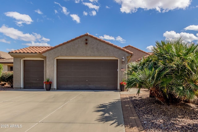 mediterranean / spanish home with driveway, an attached garage, a tiled roof, and stucco siding