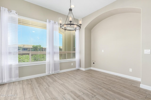 unfurnished dining area with an inviting chandelier and light hardwood / wood-style floors