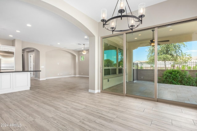 interior space with ceiling fan with notable chandelier and light wood-type flooring