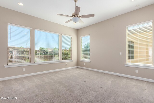 empty room with ceiling fan, light colored carpet, and a healthy amount of sunlight