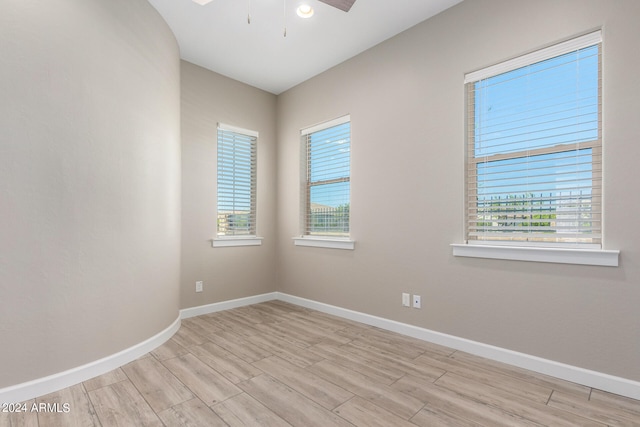 empty room with ceiling fan, plenty of natural light, and light hardwood / wood-style floors