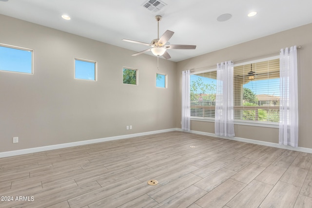 empty room with a wealth of natural light, light hardwood / wood-style floors, and ceiling fan