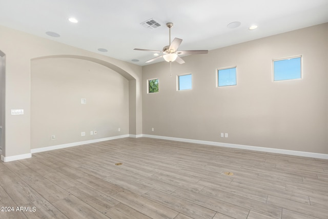 empty room with a wealth of natural light, light hardwood / wood-style floors, and ceiling fan