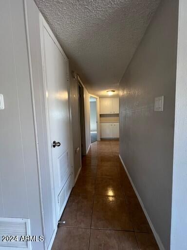 hallway featuring dark tile patterned floors and a textured ceiling