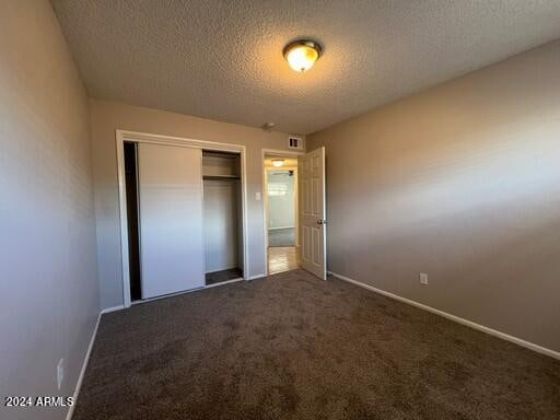 unfurnished bedroom featuring a textured ceiling, a closet, and carpet floors