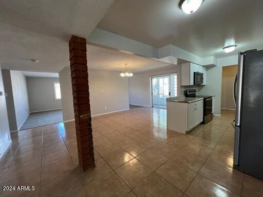 kitchen featuring white cabinets, tile patterned flooring, stainless steel appliances, and a notable chandelier