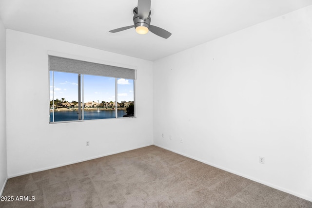 spare room featuring a ceiling fan, carpet, and baseboards