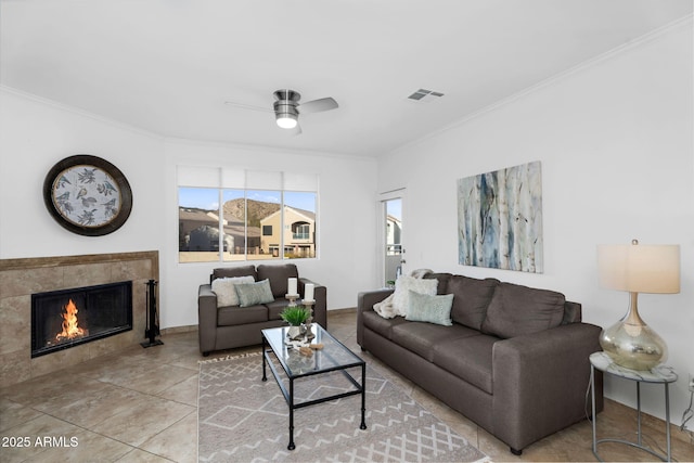 living area featuring light tile patterned flooring, a fireplace, visible vents, and crown molding