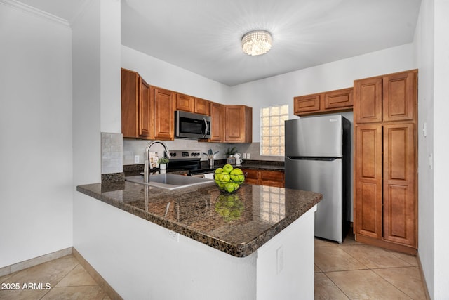 kitchen featuring light tile patterned floors, a peninsula, appliances with stainless steel finishes, and a sink