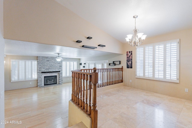 hallway featuring vaulted ceiling, an inviting chandelier, light hardwood / wood-style floors, and a healthy amount of sunlight