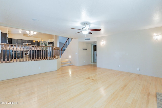 living room featuring ceiling fan with notable chandelier and light wood-type flooring