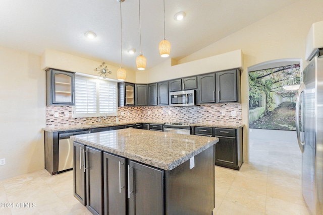 kitchen with light stone counters, lofted ceiling, decorative light fixtures, stainless steel appliances, and a center island