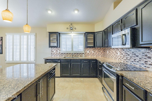 kitchen with sink, hanging light fixtures, stainless steel appliances, backsplash, and light stone countertops