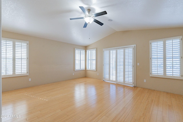 spare room featuring ceiling fan, a textured ceiling, light hardwood / wood-style flooring, and lofted ceiling