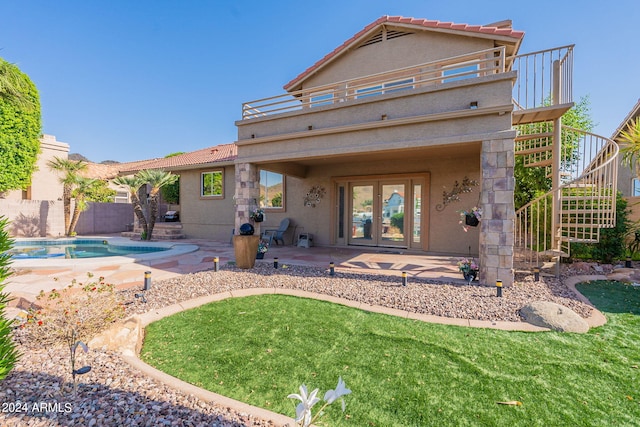 rear view of property with a patio, a fenced in pool, and french doors