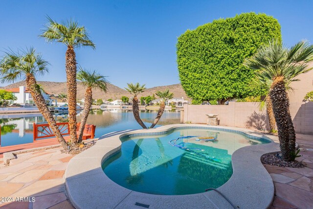 view of swimming pool featuring a patio and a water view