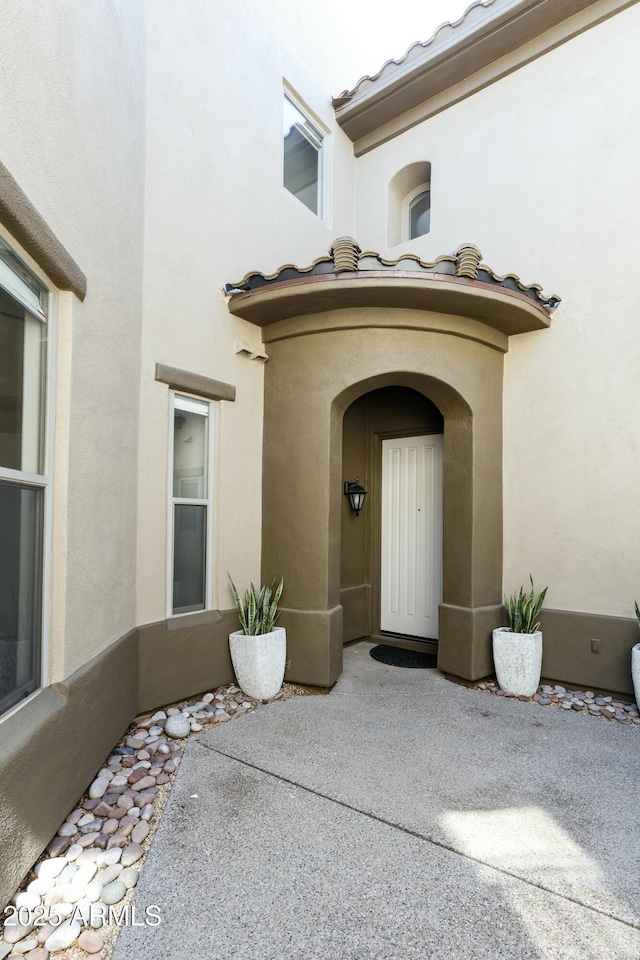 doorway to property featuring stucco siding, a patio, and a tile roof