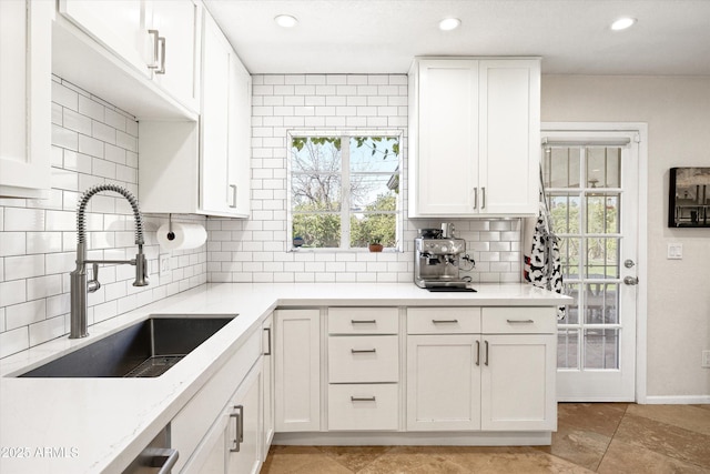 kitchen featuring a wealth of natural light, white cabinetry, a sink, and decorative backsplash