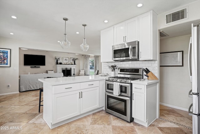 kitchen with stainless steel appliances, a peninsula, visible vents, and baseboards