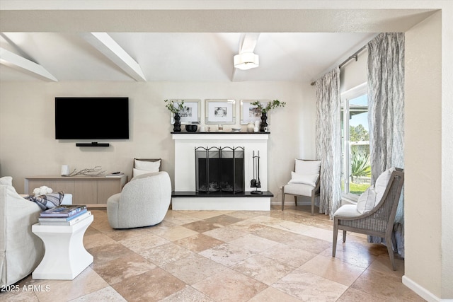 living area with a fireplace with raised hearth and stone tile floors