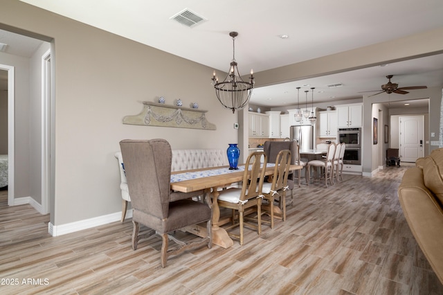 dining space featuring ceiling fan with notable chandelier and light hardwood / wood-style floors