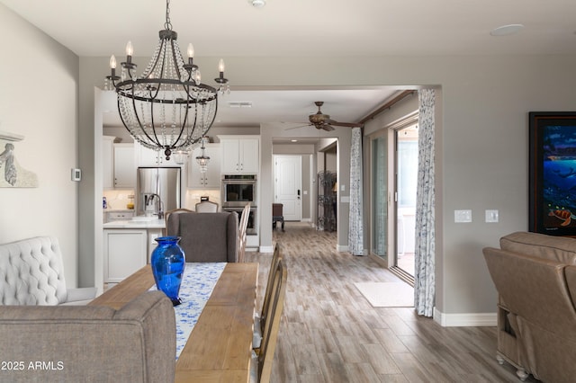 dining space featuring ceiling fan with notable chandelier and light wood-type flooring