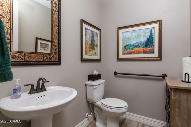 bathroom with hardwood / wood-style flooring, toilet, and sink