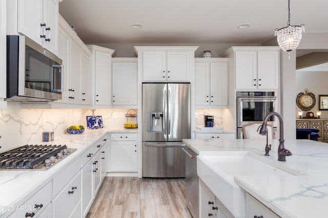 kitchen featuring appliances with stainless steel finishes, sink, pendant lighting, and white cabinets