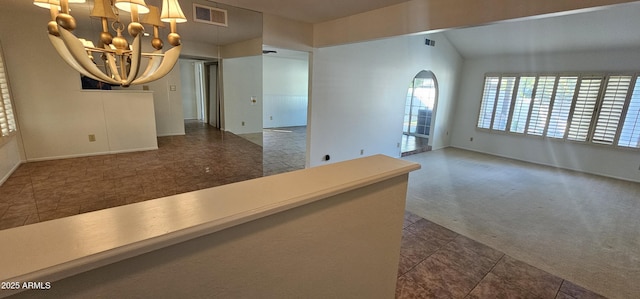 carpeted spare room featuring vaulted ceiling and a chandelier