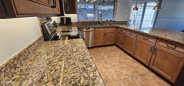 kitchen featuring sink, hanging light fixtures, dark stone countertops, kitchen peninsula, and stainless steel appliances