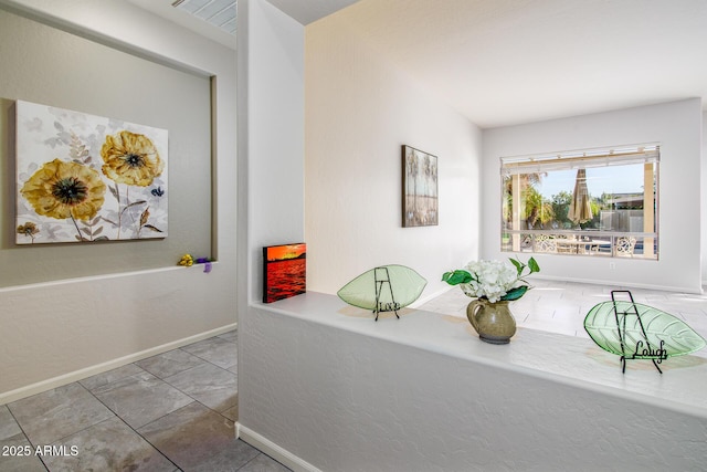 hall with baseboards and tile patterned floors