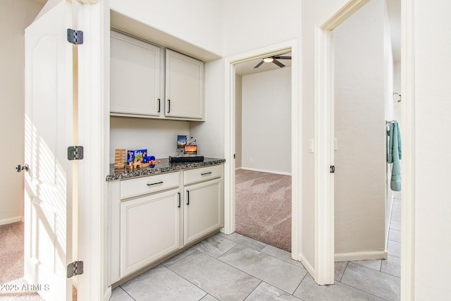 bar featuring light carpet, baseboards, and light tile patterned floors