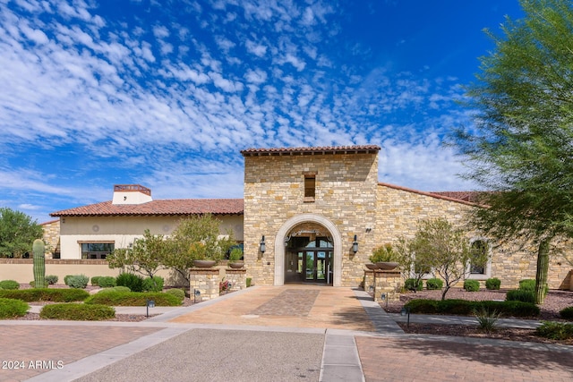 exterior space featuring stone siding, french doors, a tiled roof, and stucco siding