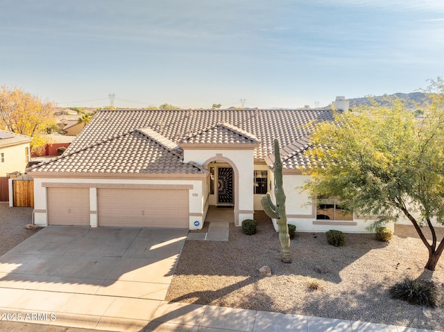 mediterranean / spanish house featuring a garage, stucco siding, driveway, and a tiled roof