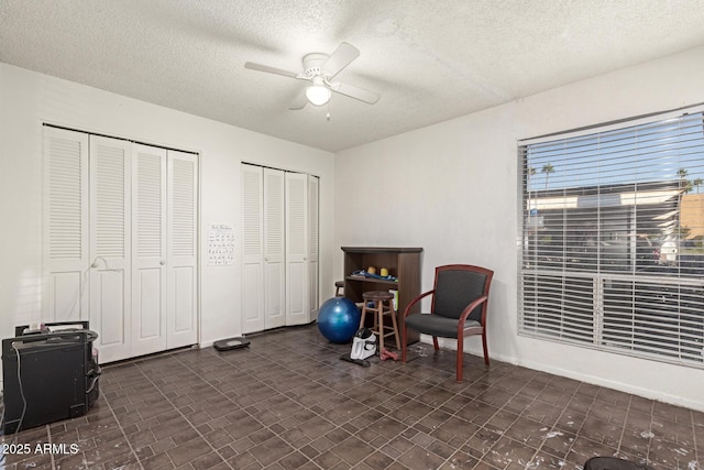 exercise room with a textured ceiling and ceiling fan