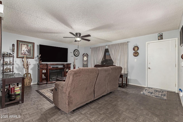 living room featuring dark parquet flooring, ceiling fan, and a textured ceiling