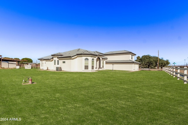 back of property featuring fence, a tiled roof, stucco siding, central AC unit, and a yard