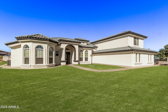 rear view of property with a lawn, a tile roof, and stucco siding