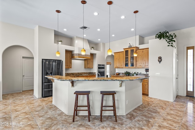 kitchen with a large island, stainless steel appliances, a kitchen breakfast bar, and arched walkways