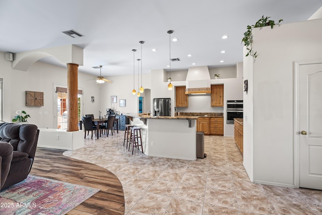 kitchen featuring a breakfast bar area, visible vents, stainless steel appliances, open floor plan, and custom exhaust hood