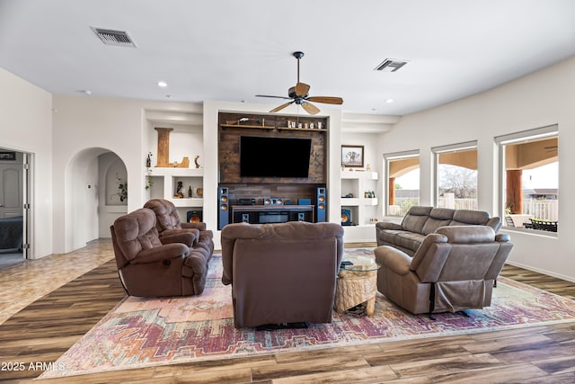 living area featuring visible vents, arched walkways, a ceiling fan, and wood finished floors