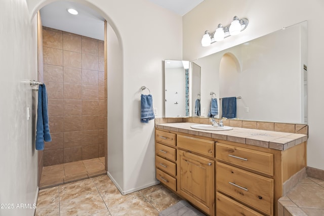 full bathroom with a walk in shower, vanity, and baseboards