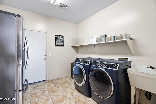clothes washing area featuring visible vents, separate washer and dryer, laundry area, and a sink