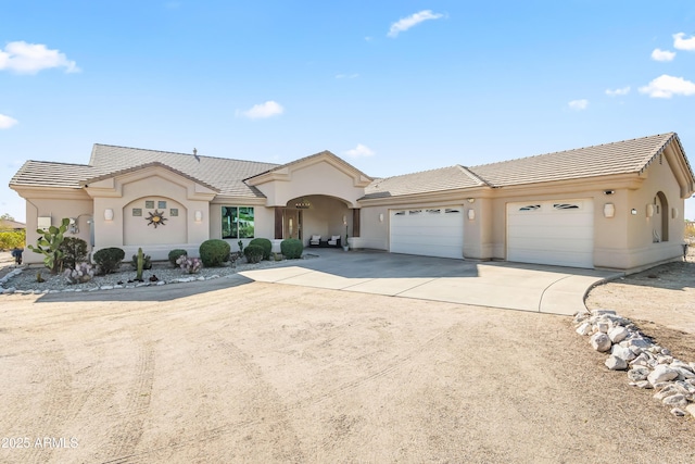 view of front of property with stucco siding, concrete driveway, an attached garage, and a tile roof